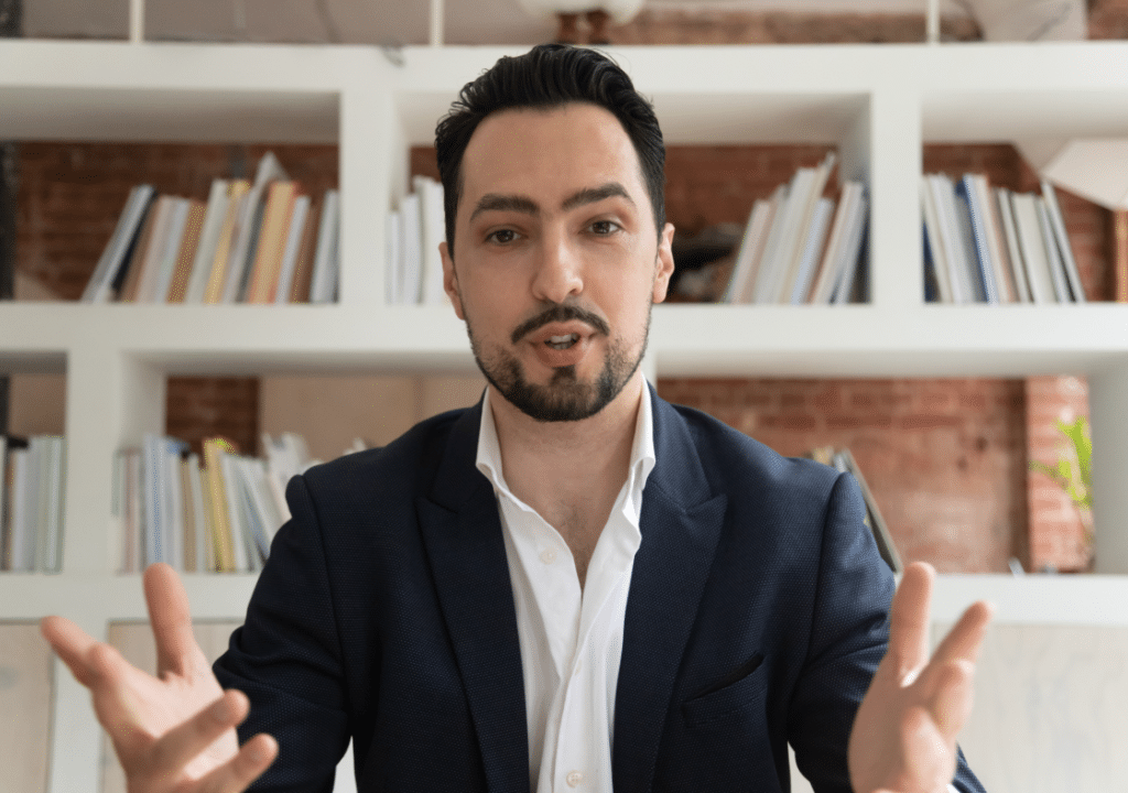 A man in a suit gesturing with his hands.