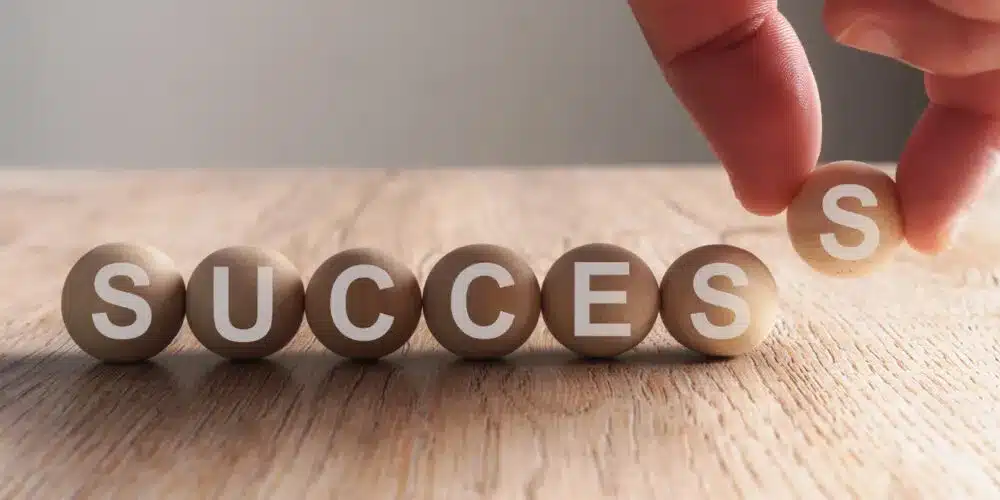 The image shows a close-up, slightly angled shot of seven round, wooden blocks arranged in a row on a light-colored wooden surface.
