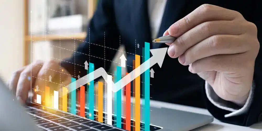 The image features a business professional analyzing a graph on a laptop, with colorful bar charts and an upward-trending arrow symbolizing growth and success. It conveys themes of financial improvement, business strategy, and professional achievement.