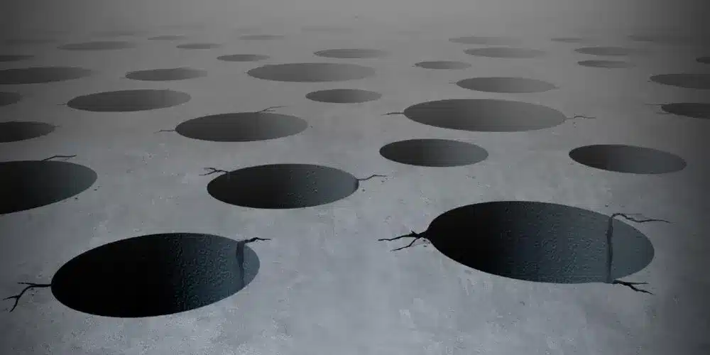 The image presents a digitally created, surreal scene of a flat, gray surface peppered with numerous oval-shaped, dark holes.